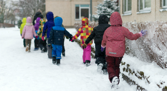 Schoolchildren holding hands while walking through snow