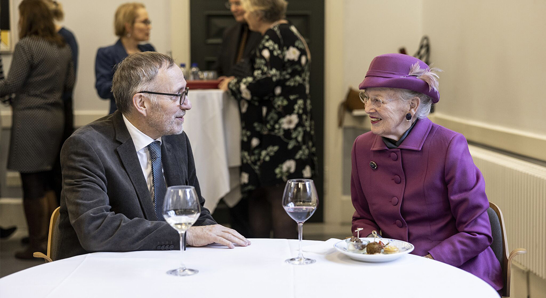 Professor Thue Schwartz seated at a table with Her Majesty the Queen of Denmark