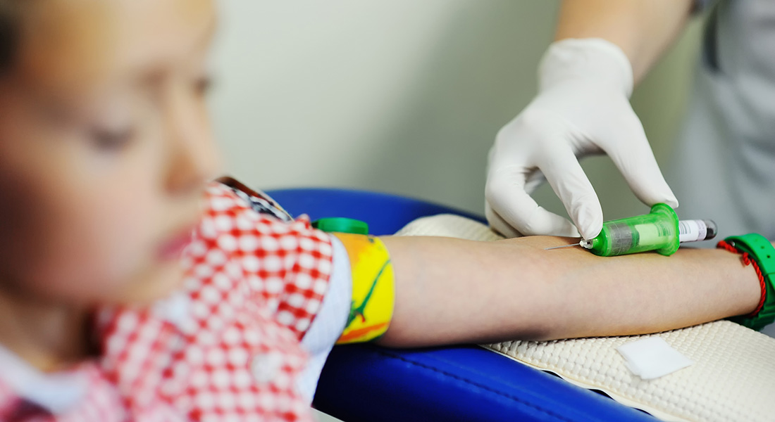 The photo shows a young boy having some blood taken.