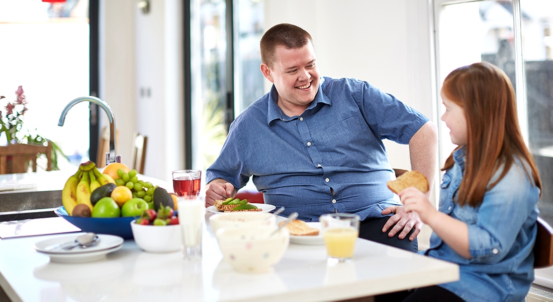 Picture of a dad and his daughter sitting at a kitchen counter while eating