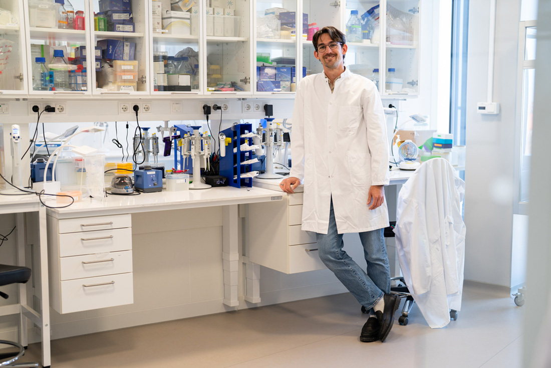 Photo of Nigel standing in a laboratory while wearing a lab coat